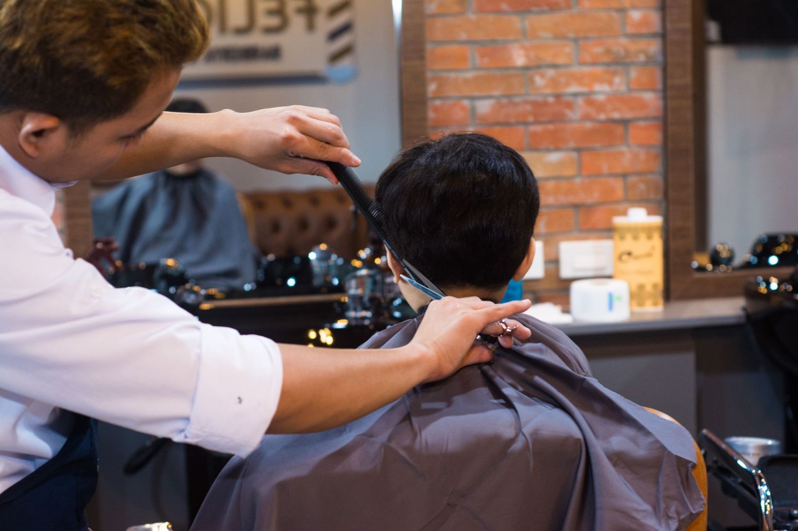 Barber carefully cutting a client's hair in a barbershop