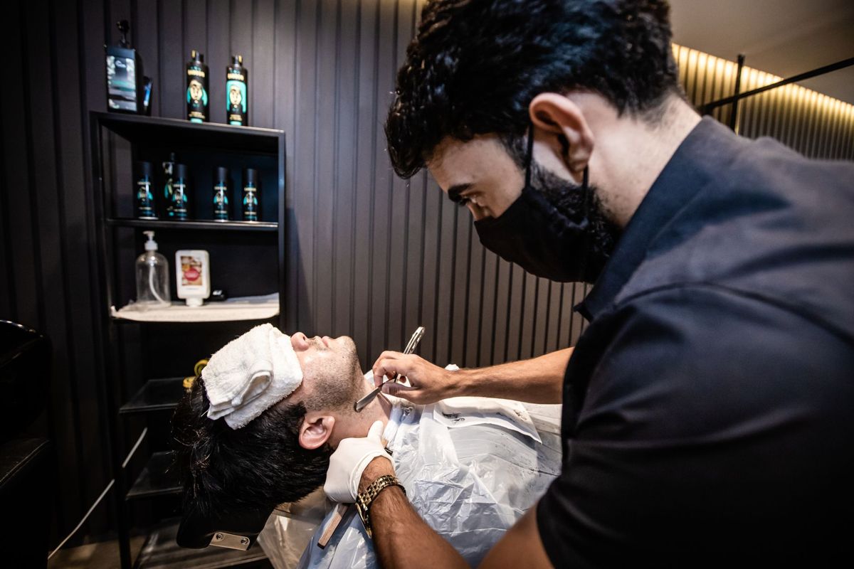 Barber carefully grooming a client's face with a straight razor