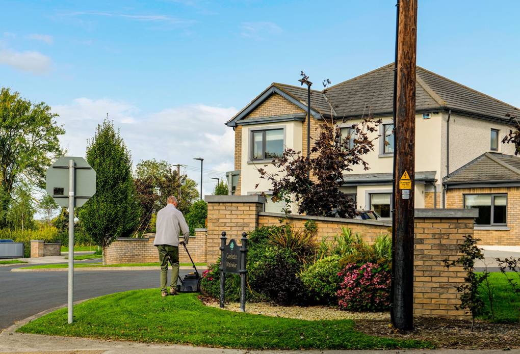 Lawn mowing outside a home with a lush garden